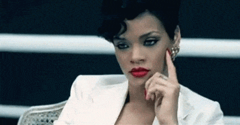 Rihanna tapping the side of her head with her finger, in thought.