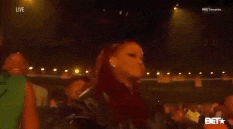 Rihanna tapping the side of her head with her finger, in thought.